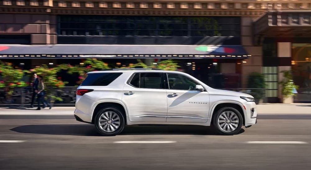 A white 2023 Chevy Traverse driving in a city.