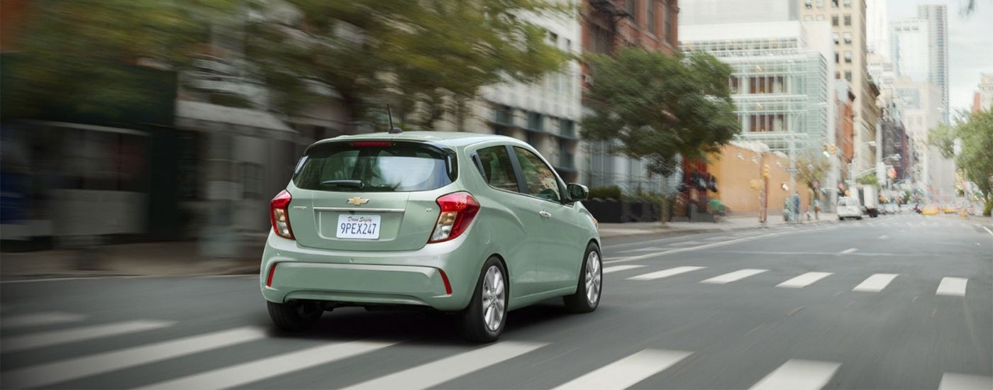 Green 2017 Chevy Spark driving on a city street
