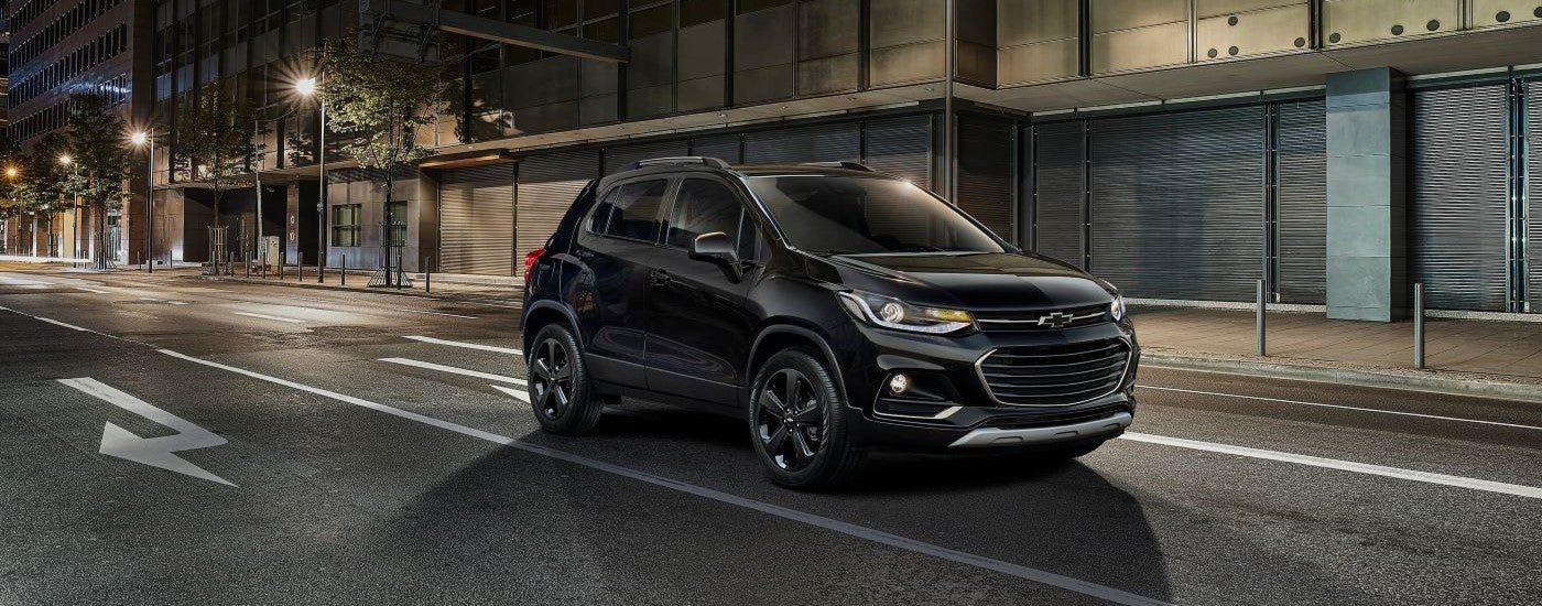 Black 2018 Chevy Trax driving down a city street.