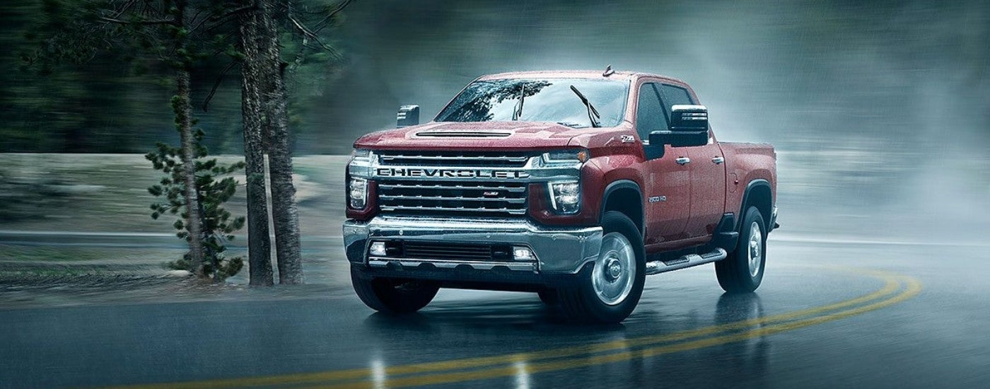 Red 2022 Chevy Silverado 2500 HD driving to a used car dealership near Port Huron.