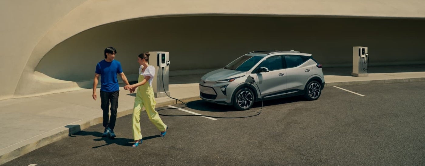 Couple walking past a grey 2023 Chevy Bolt EUV
