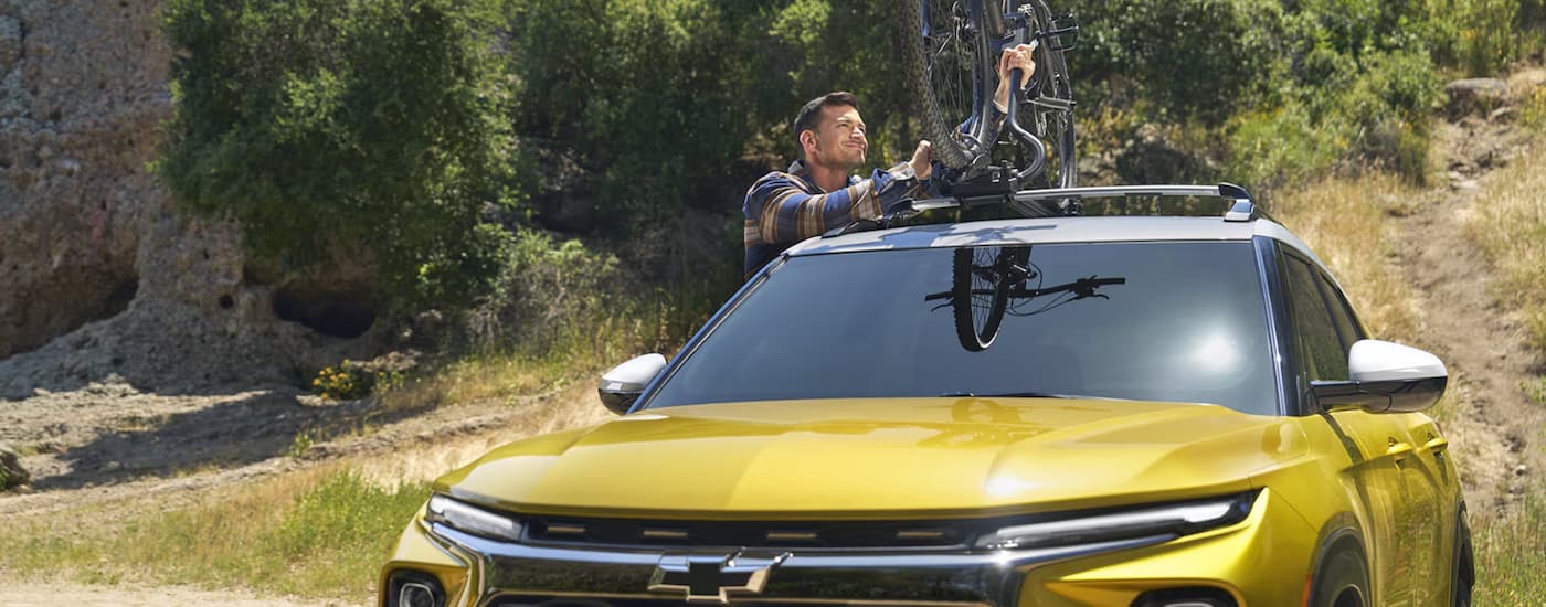Person mounting bicycle to the roof of a yellow 2026 Chevy Trailblazer.