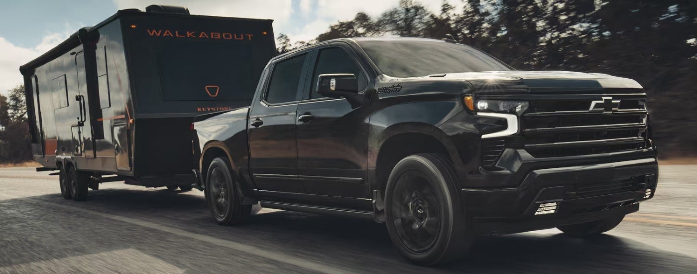 Black 2026 Chevy Silverado 1500 High Country towing a camper.