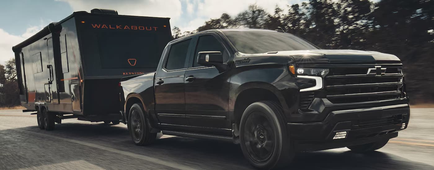 Black 2026 Chevy Silverado 1500 High Country towing a trailer.