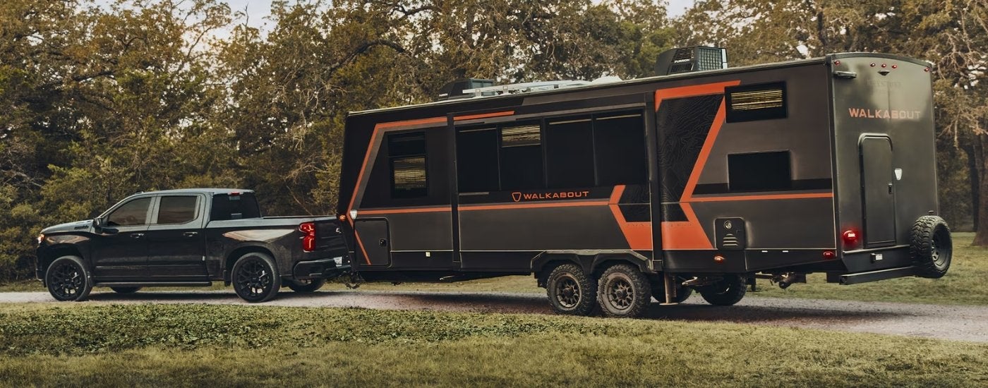 A black 2026 Chevy Silverado 1500 High Country towing a trailer