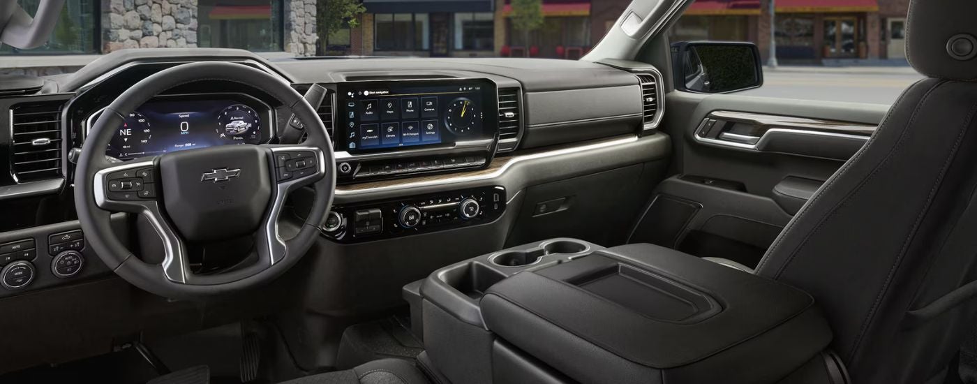 The front black interior of a 2026 Chevy Silverado 1500 showing the steering wheel and infotainment display.