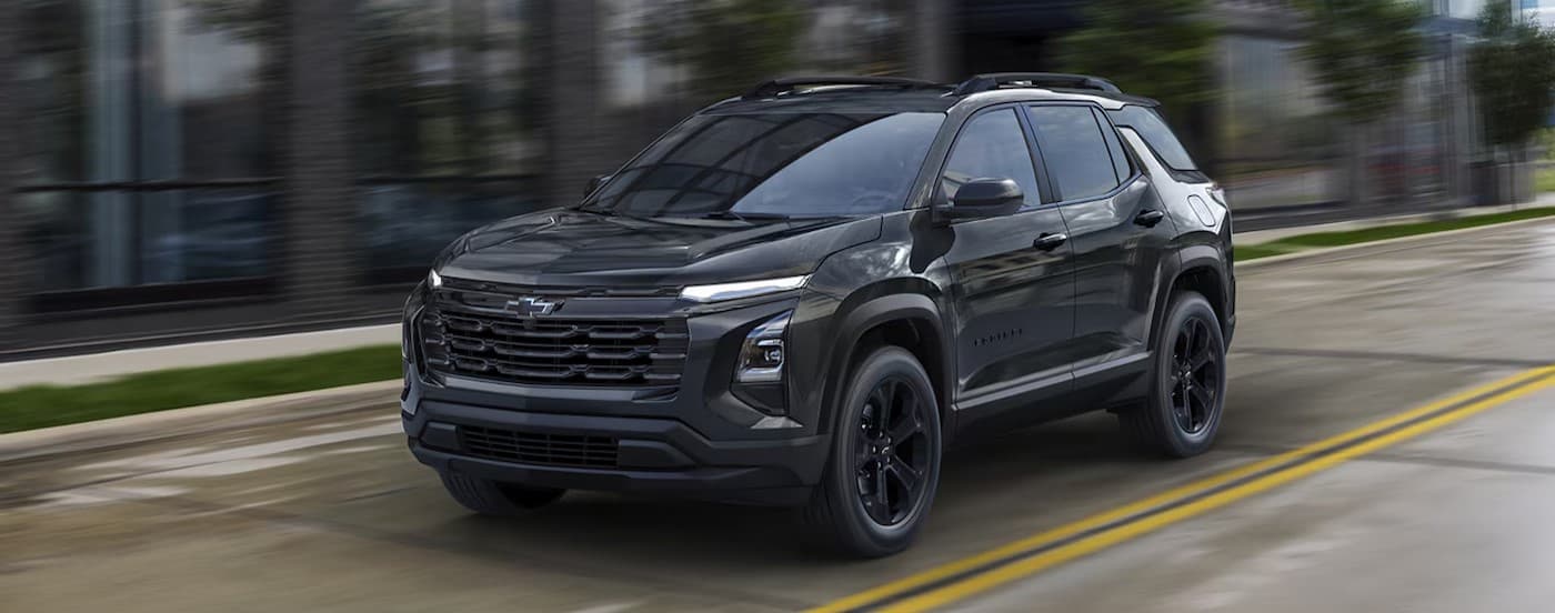 A black 2026 Chevy Equinox driving to a Chevy dealer near Lenox.