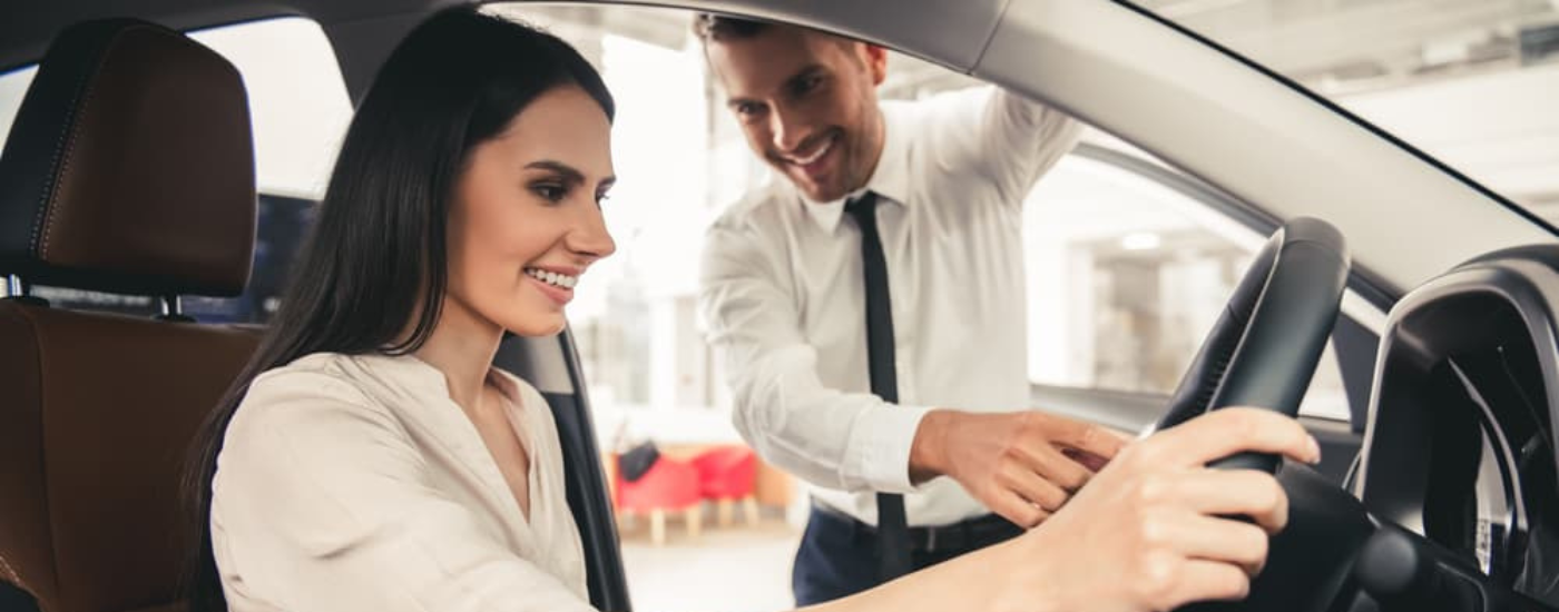A woiman inside a vehicle speaking to a salesman